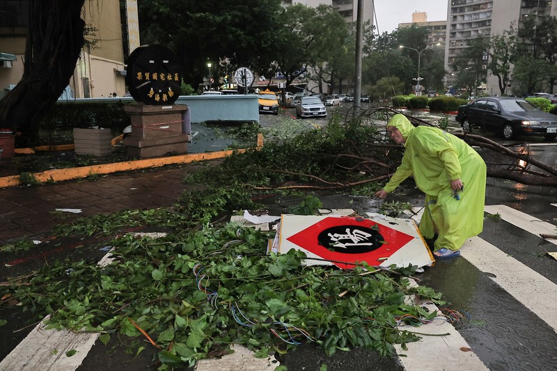 Orang-orang membersihkan jalan setelah Topan Krathon mendarat di Kaohsiung, Taiwan, 4 Oktober 2024. (REUTERS/Ann Wang)