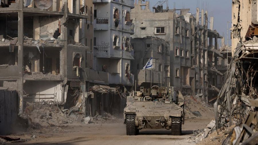 Sebuah kendaraan lapis baja melaju sementara bangunan-bangunan yang rusak terlihat di latar belakang, di tengah operasi darat yang sedang berlangsung oleh tentara Israel terhadap kelompok Islam Palestina Hamas, di Jalur Gaza, 13 September 2024. (REUTERS/Amir Cohen)