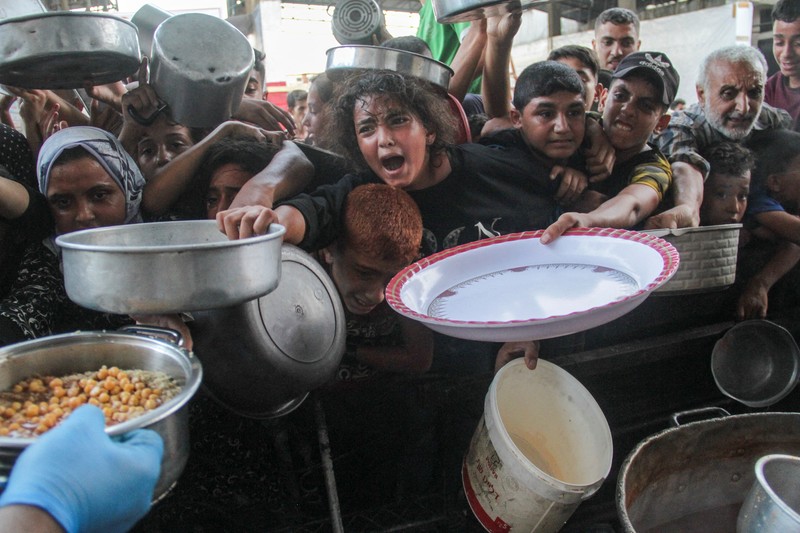 Warga Palestina berjalan melewati rumah-rumah yang hancur, di tengah konflik yang sedang berlangsung antara Israel dan Hamas, di kamp pengungsi Jabalia, di Jalur Gaza utara, 22 Februari 2024. (REUTERS/Mahmoud Issa/File Foto)