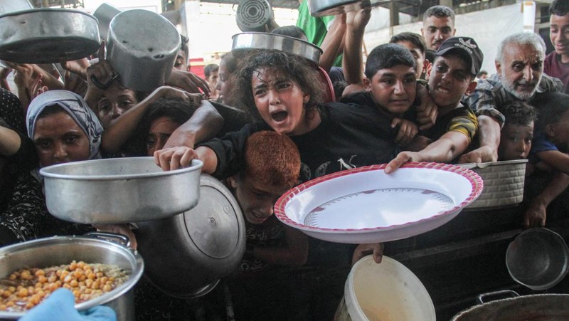 Warga Palestina berjalan melewati rumah-rumah yang hancur, di tengah konflik yang sedang berlangsung antara Israel dan Hamas, di kamp pengungsi Jabalia, di Jalur Gaza utara, 22 Februari 2024. (REUTERS/Mahmoud Issa/File Foto)