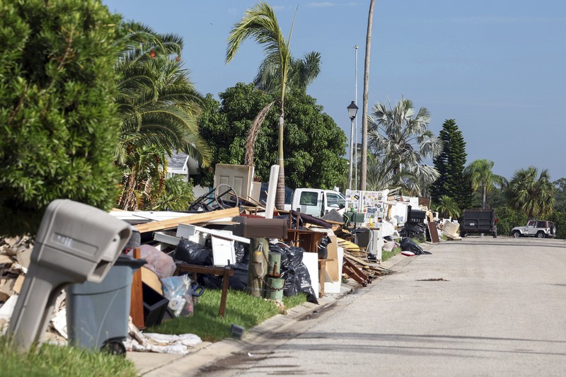 APTOPIX Hurricane Milton Weather A tattered American flag flaps outside a home as furniture and household items damaged by Hurricane Helene flooding sit piled along the street awaiting pickup, ahead of the arrival of Hurricane Milton, in Holmes Beach on Anna Maria Island, Fla., Tuesday, Oct. 8, 2024. (AP Photo/Rebecca Blackwell)