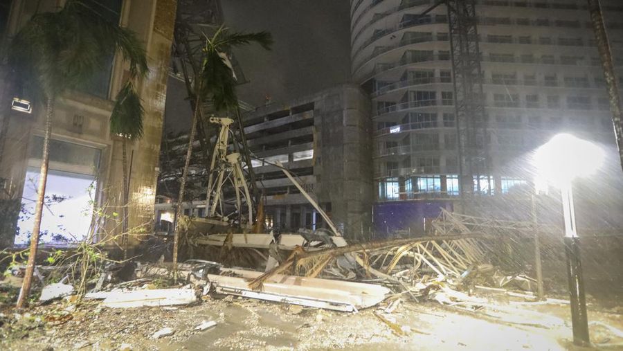 Debris covers the ground near a crane that fell onto a building along 1st Avenue South in St. Petersburg, Fla., as Hurricane Milton's strong winds tore through the area Thursday, Oct. 10, 2024. (Chris Urso/Tampa Bay Times via AP)