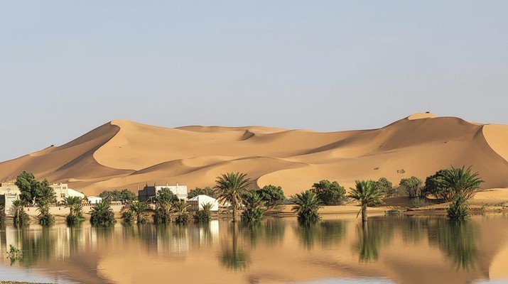 Sebuah Oasis tercermin di sebuah danau yang disebabkan oleh hujan lebat di kota gurun Merzouga, dekat Rachidia, tenggara Maroko, Rabu, 2 Oktober 2024. (AP Photo)