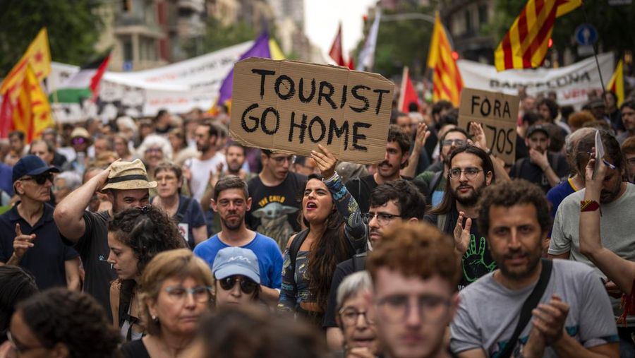 Demonstrators march shouting slogans against the Formula 1 Barcelona Fan Festival in downtown Barcelona, Spain, Wednesday, June 19, 2024. Barcelona City Hall announced last month that it would not renew any tourist apartment licenses after they expire in 2028. (AP Photo/Emilio Morenatti)