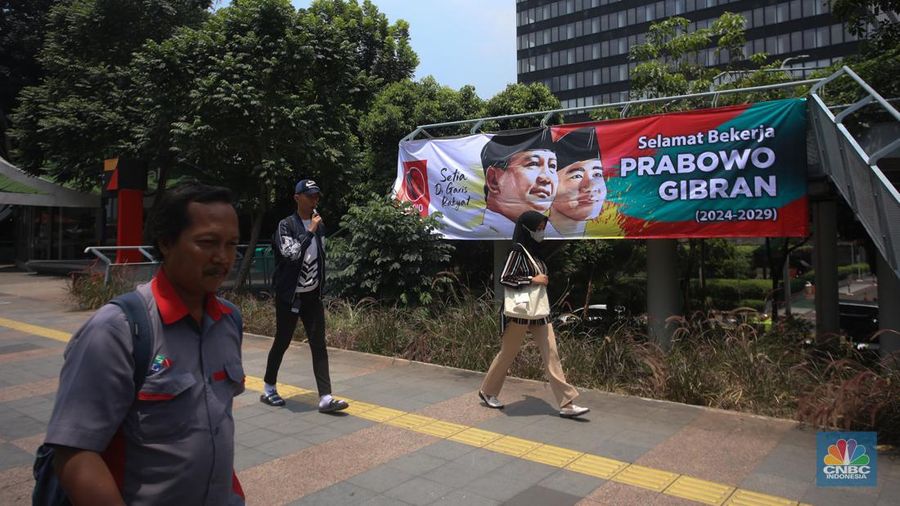 Warga berjalan di dekat spanduk bertuliskan 'Selamat Bekerja Prabowo-Gibran' di Jakarta, Kamis (17/10/2024). (CNBC Indonesia/Faisal Rahman)