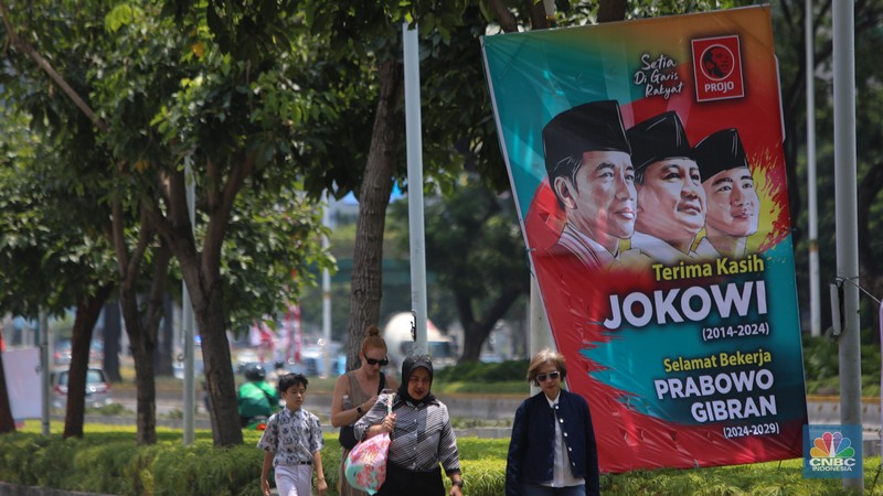 Warga berjalan di dekat spanduk bertuliskan 'Selamat Bekerja Prabowo-Gibran' di Jakarta, Kamis (17/10/2024). (CNBC Indonesia/Faisal Rahman)