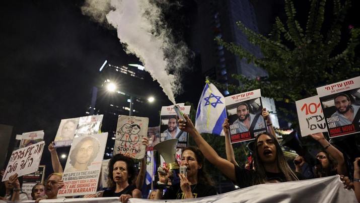 A person holds a smoke flare, as families and supporters of hostages kidnapped during the deadly October 7, 2023 attack, protest to demand their immediate release, amid the ongoing conflict in Gaza between Israel and Hamas, in Tel Aviv, Israel, October 17, 2024. REUTERS/Violeta Santos Moura
