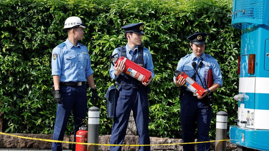 Polisi membawa alat pemadam kebakaran di dekat lokasi mobil tersangkut di pagar, dekat pintu masuk kantor Perdana Menteri di Tokyo, Jepang, Sabtu (19/10). Setelah seorang Pria (40) ditangkap di Tokyo setelah melemparkan bom molotov ke markas partai berkuasa. Peristiwa ini terjadi menjelang pemilihan umum. (REUTERS/Kim Kyung-Hoon)