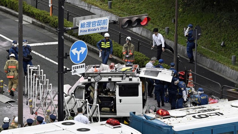 Polisi membawa alat pemadam kebakaran di dekat lokasi mobil tersangkut di pagar, dekat pintu masuk kantor Perdana Menteri di Tokyo, Jepang, Sabtu (19/10). Setelah seorang Pria (40) ditangkap di Tokyo setelah melemparkan bom molotov ke markas partai berkuasa. Peristiwa ini terjadi menjelang pemilihan umum. (REUTERS/Kim Kyung-Hoon)