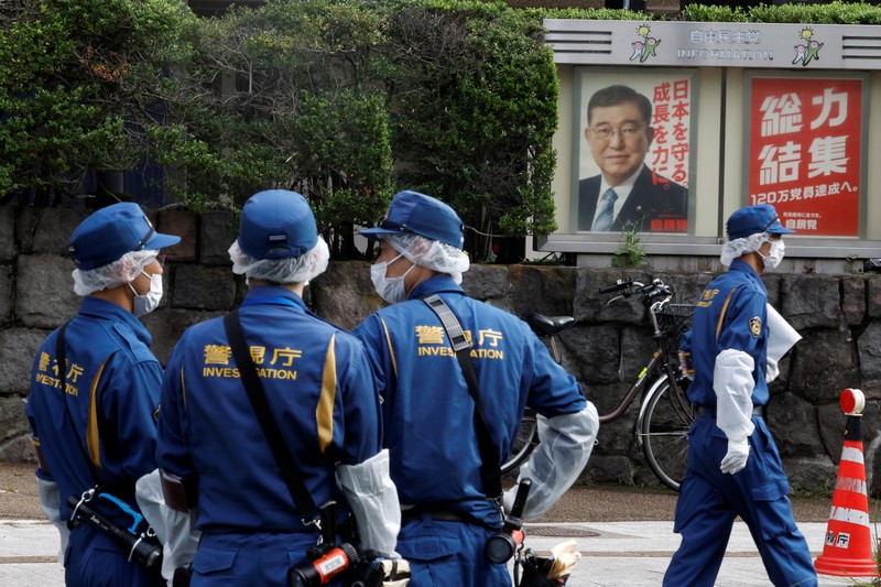 Polisi membawa alat pemadam kebakaran di dekat lokasi mobil tersangkut di pagar, dekat pintu masuk kantor Perdana Menteri di Tokyo, Jepang, Sabtu (19/10). Setelah seorang Pria (40) ditangkap di Tokyo setelah melemparkan bom molotov ke markas partai berkuasa. Peristiwa ini terjadi menjelang pemilihan umum. (REUTERS/Kim Kyung-Hoon)