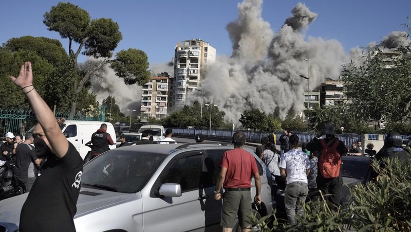 Orang-orang menyaksikan bangunan runtuh setelah terkena serangan udara Israel di Ghobeiry, Beirut, Lebanon, Selasa, 22 Oktober 2024. (AP Photo/Bilal Hussein)