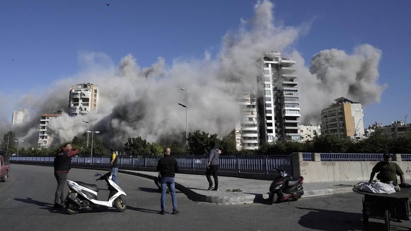 Orang-orang menyaksikan bangunan runtuh setelah terkena serangan udara Israel di Ghobeiry, Beirut, Lebanon, Selasa, 22 Oktober 2024. (AP Photo/Bilal Hussein)