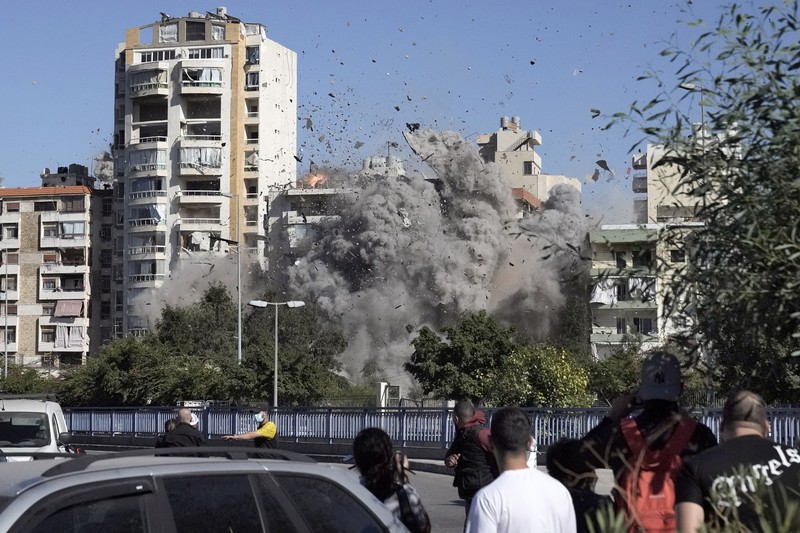 Orang-orang menyaksikan bangunan runtuh setelah terkena serangan udara Israel di Ghobeiry, Beirut, Lebanon, Selasa, 22 Oktober 2024. (AP Photo/Bilal Hussein)
