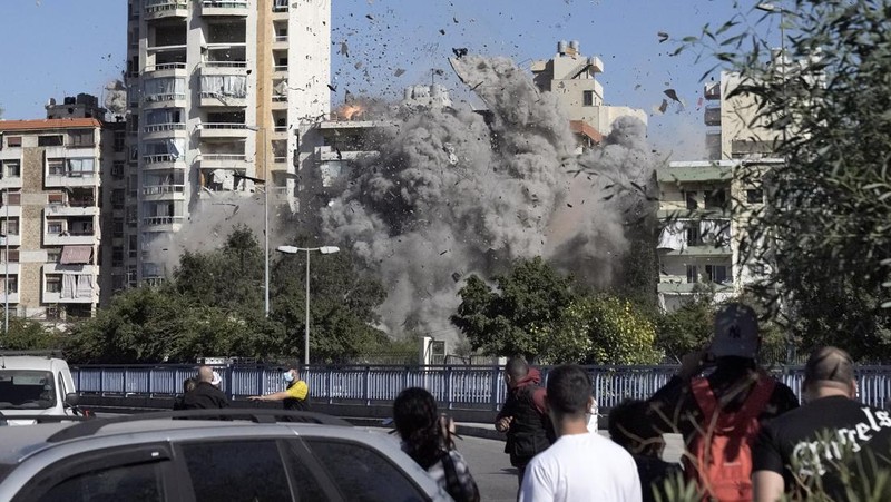 Orang-orang menyaksikan bangunan runtuh setelah terkena serangan udara Israel di Ghobeiry, Beirut, Lebanon, Selasa, 22 Oktober 2024. (AP Photo/Bilal Hussein)