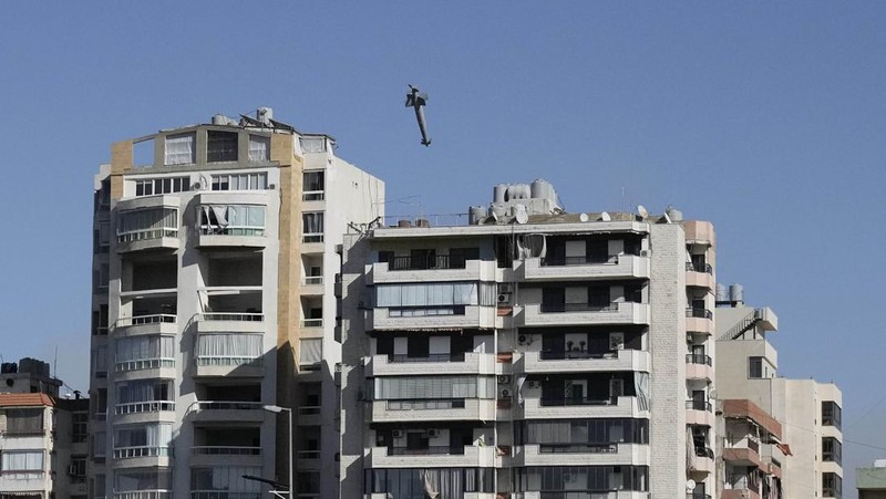 Orang-orang menyaksikan bangunan runtuh setelah terkena serangan udara Israel di Ghobeiry, Beirut, Lebanon, Selasa, 22 Oktober 2024. (AP Photo/Bilal Hussein)