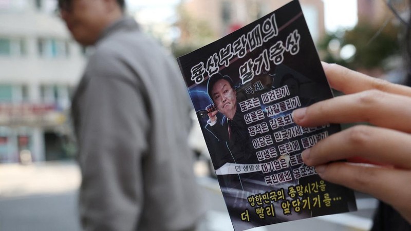 People look at a North Korean propaganda leaflet denouncing South Korean President Yoon Suk Yeol and his wife Kim Keon Hee, apparently carried by balloons sent from North Korea, near the Presidential Office in Seoul, South Korea, October 24, 2024.   REUTERS/Kim Hong-Ji