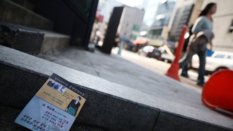 People look at a North Korean propaganda leaflet denouncing South Korean President Yoon Suk Yeol and his wife Kim Keon Hee, apparently carried by balloons sent from North Korea, near the Presidential Office in Seoul, South Korea, October 24, 2024.   REUTERS/Kim Hong-Ji