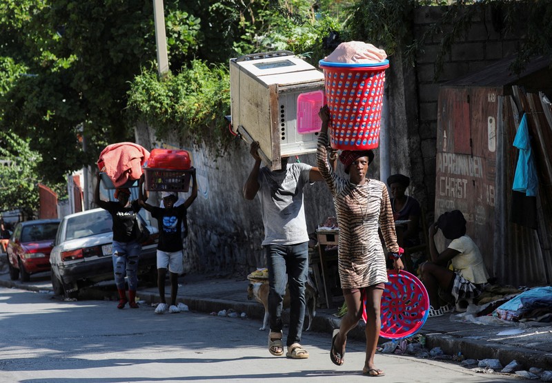 Seorang pria membawa sofa saat melarikan diri dari rumahnya dari kekerasan geng, di Port-au-Prince, Haiti, 26 Oktober 2024. 
 (REUTERS/Ralph Tedy Erol)