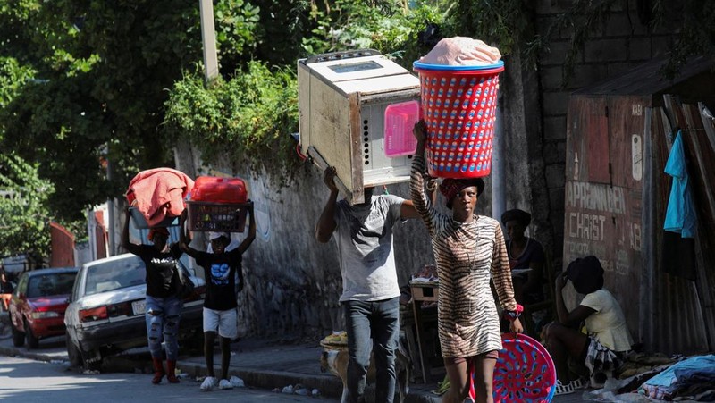 Seorang pria membawa sofa saat melarikan diri dari rumahnya dari kekerasan geng, di Port-au-Prince, Haiti, 26 Oktober 2024. 
 (REUTERS/Ralph Tedy Erol)