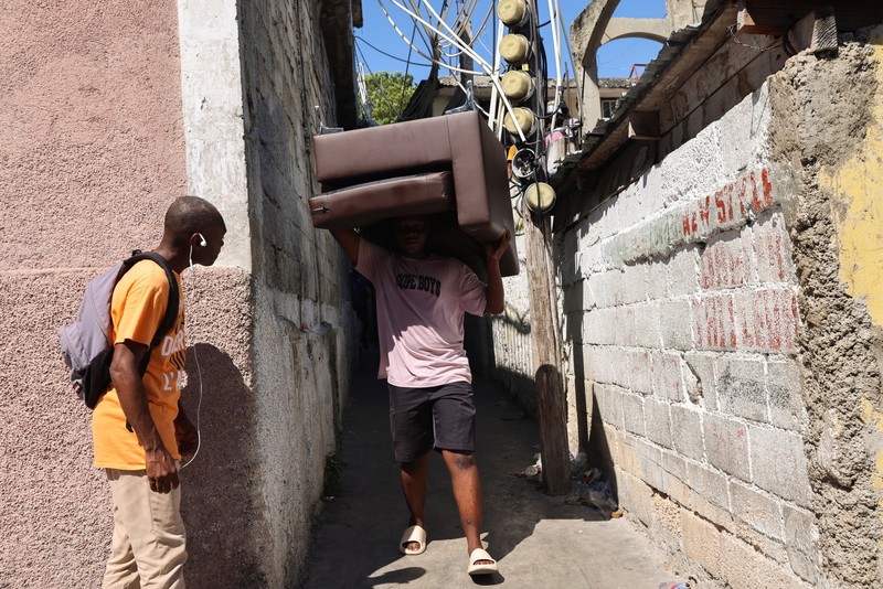Seorang pria membawa sofa saat melarikan diri dari rumahnya dari kekerasan geng, di Port-au-Prince, Haiti, 26 Oktober 2024. 
 (REUTERS/Ralph Tedy Erol)