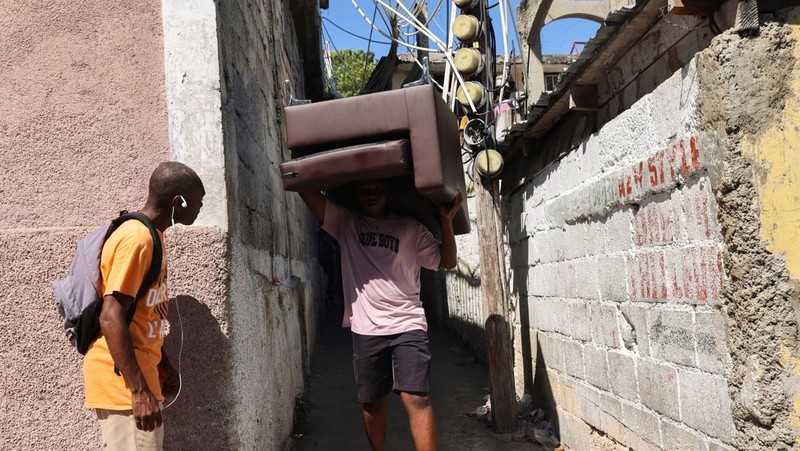 Seorang pria membawa sofa saat melarikan diri dari rumahnya dari kekerasan geng, di Port-au-Prince, Haiti, 26 Oktober 2024. 
 (REUTERS/Ralph Tedy Erol)