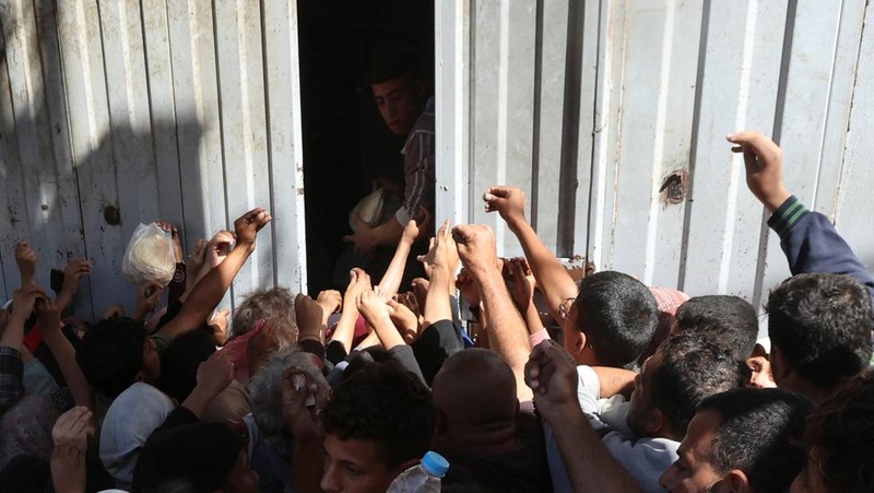 Warga Palestina berkumpul untuk membeli roti dari toko roti, di tengah konflik Israel-Hamas, di Deir Al-Balah di Jalur Gaza tengah, 24 Oktober 2024. (REUTERS/Ramadan Abed)