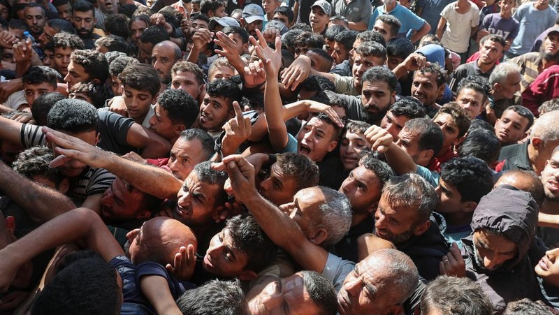 Warga Palestina berkumpul untuk membeli roti dari toko roti, di tengah konflik Israel-Hamas, di Deir Al-Balah di Jalur Gaza tengah, 24 Oktober 2024. (REUTERS/Ramadan Abed)