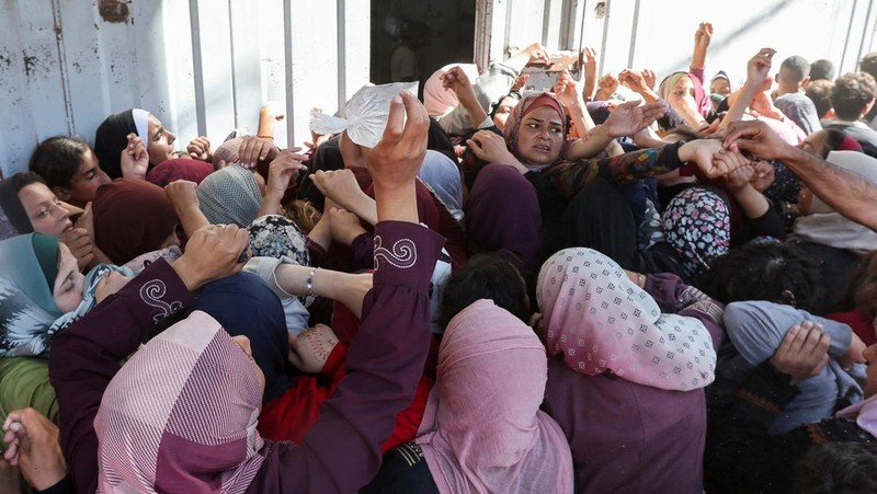 Warga Palestina berkumpul untuk membeli roti dari toko roti, di tengah konflik Israel-Hamas, di Deir Al-Balah di Jalur Gaza tengah, 24 Oktober 2024. (REUTERS/Ramadan Abed)