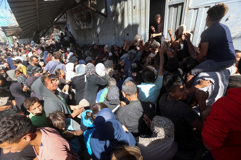 Warga Palestina berkumpul untuk membeli roti dari toko roti, di tengah konflik Israel-Hamas, di Deir Al-Balah di Jalur Gaza tengah, 24 Oktober 2024. Warga Palestina berkumpul untuk membeli roti dari toko roti, di tengah konflik Israel-Hamas, di Deir Al-Balah di Jalur Gaza tengah, 24 Oktober 2024. (REUTERS/Ramadan Abed)