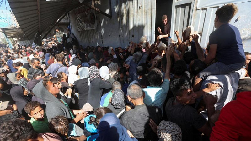 Warga Palestina berkumpul untuk membeli roti dari toko roti, di tengah konflik Israel-Hamas, di Deir Al-Balah di Jalur Gaza tengah, 24 Oktober 2024. (REUTERS/Ramadan Abed)