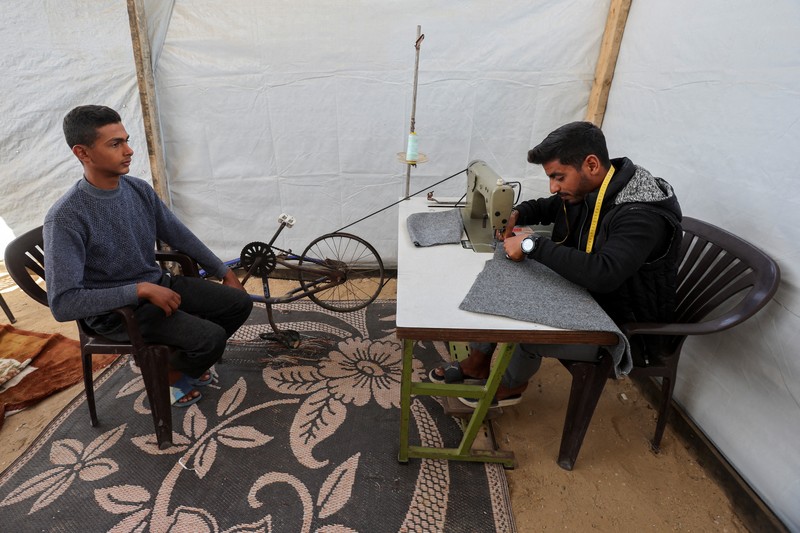 Warga Palestina yang mengungsi menyalakan api di tenda mereka saat mereka tinggal di pemakaman, di tengah konflik Israel-Hamas, di Khan Younis, di Jalur Gaza selatan, 27 Oktober 2024. (REUTERS/Mohammed Salem)