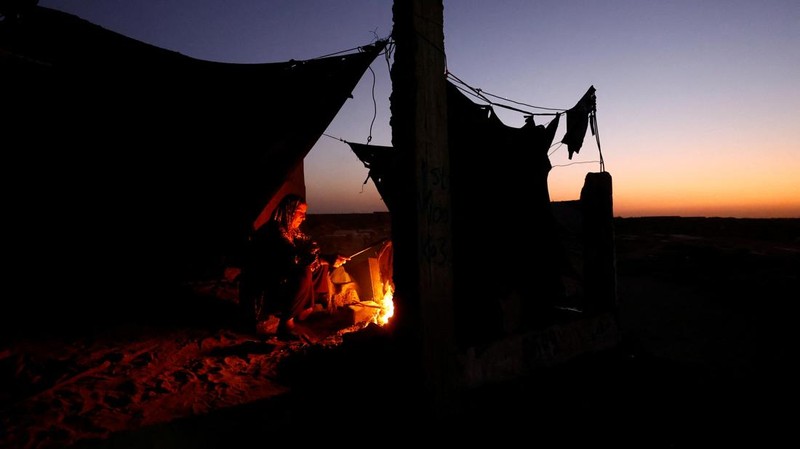 Warga Palestina yang mengungsi menyalakan api di tenda mereka saat mereka tinggal di pemakaman, di tengah konflik Israel-Hamas, di Khan Younis, di Jalur Gaza selatan, 27 Oktober 2024. (REUTERS/Mohammed Salem)