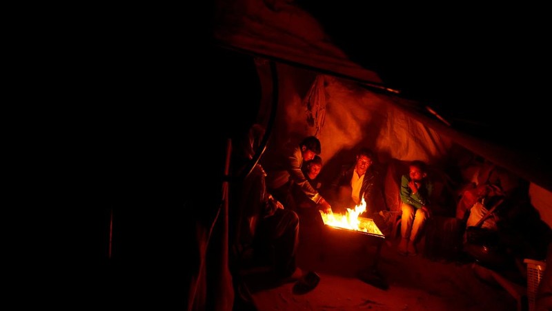 Warga Palestina yang mengungsi menyalakan api di tenda mereka saat mereka tinggal di pemakaman, di tengah konflik Israel-Hamas, di Khan Younis, di Jalur Gaza selatan, 27 Oktober 2024. (REUTERS/Mohammed Salem)