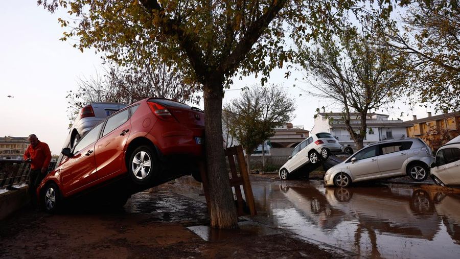 Residents stand outside their homes next to damaged belongings after floods in Utiel, Spain, October 30, 2024. REUTERS/Susana Vera
