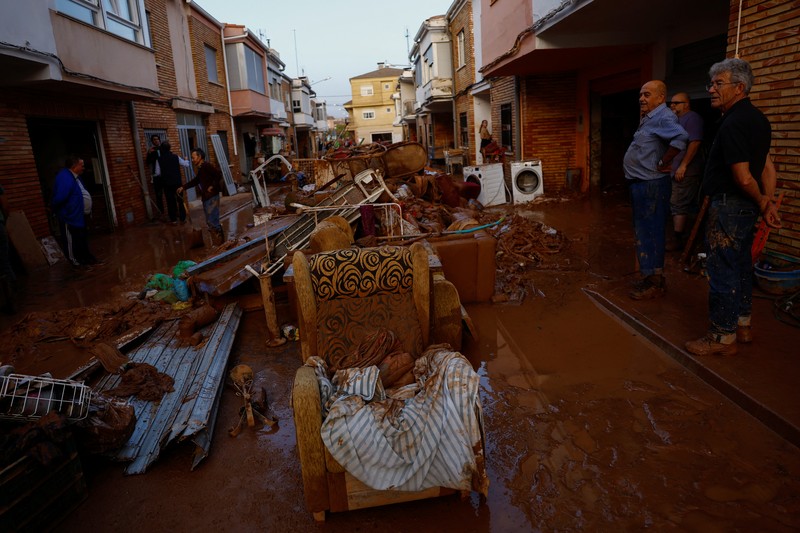 Residents stand outside their homes next to damaged belongings after floods in Utiel, Spain, October 30, 2024. REUTERS/Susana Vera