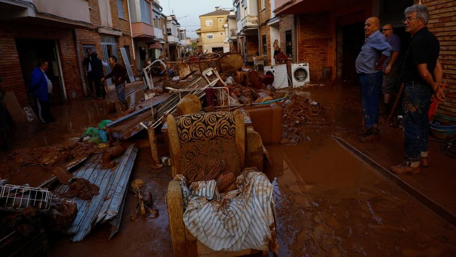 Residents stand outside their homes next to damaged belongings after floods in Utiel, Spain, October 30, 2024. REUTERS/Susana Vera