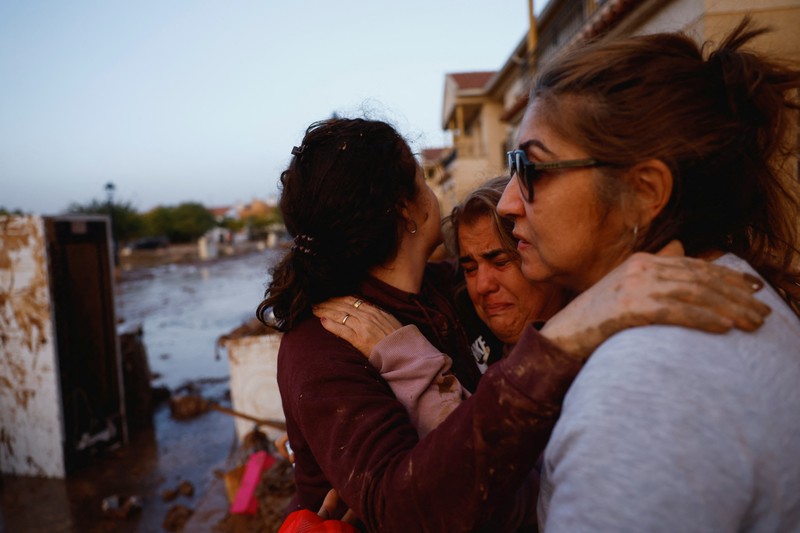 Residents stand outside their homes next to damaged belongings after floods in Utiel, Spain, October 30, 2024. REUTERS/Susana Vera