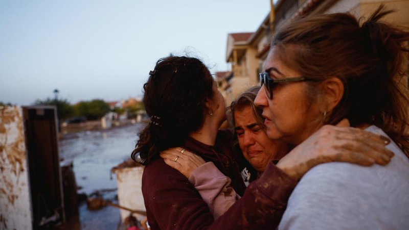 Residents stand outside their homes next to damaged belongings after floods in Utiel, Spain, October 30, 2024. REUTERS/Susana Vera