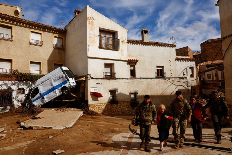 Residents stand outside their homes next to damaged belongings after floods in Utiel, Spain, October 30, 2024. REUTERS/Susana Vera