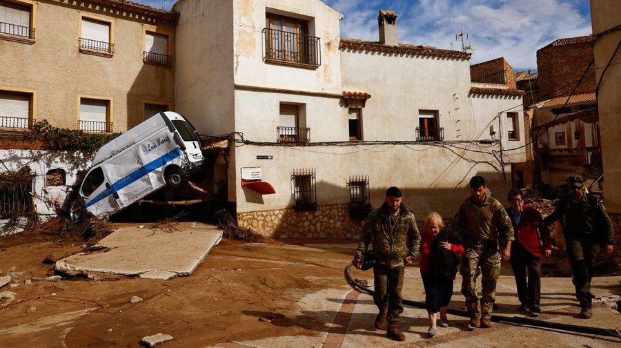Residents stand outside their homes next to damaged belongings after floods in Utiel, Spain, October 30, 2024. REUTERS/Susana Vera