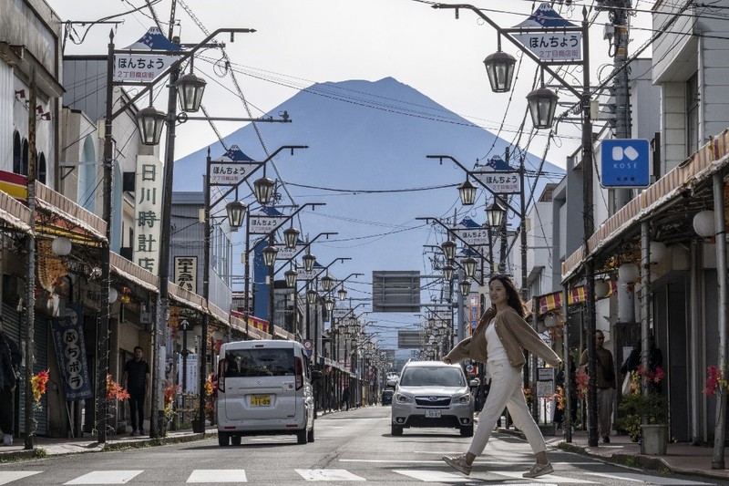 Warga beraktivitas dengan latar belakang Gunung Fuji, gunung tertinggi di Jepang dengan ketinggian 3.776 meter (12.460 kaki), di Fujikawaguchiko, prefektur Yamanashi pada tanggal 31 Oktober 2024. (AFP/YUICHI YAMAZAKI)