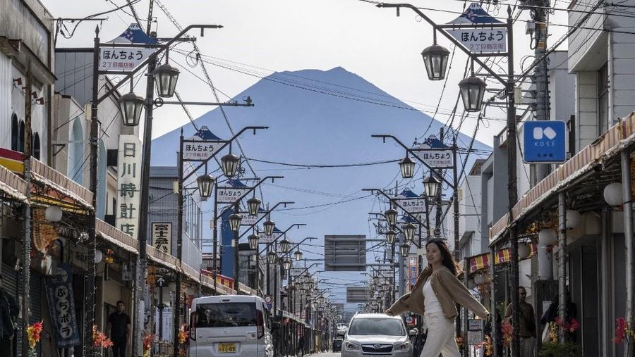 Warga beraktivitas dengan latar belakang Gunung Fuji, gunung tertinggi di Jepang dengan ketinggian 3.776 meter (12.460 kaki), di Fujikawaguchiko, prefektur Yamanashi pada tanggal 31 Oktober 2024. (AFP/YUICHI YAMAZAKI)