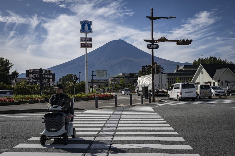 Warga beraktivitas dengan latar belakang Gunung Fuji, gunung tertinggi di Jepang dengan ketinggian 3.776 meter (12.460 kaki), di Fujikawaguchiko, prefektur Yamanashi pada tanggal 31 Oktober 2024. (AFP/YUICHI YAMAZAKI)
