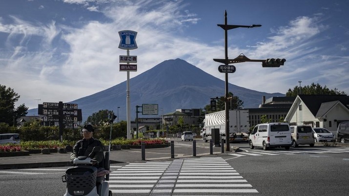 Warga beraktivitas dengan latar belakang Gunung Fuji, gunung tertinggi di Jepang dengan ketinggian 3.776 meter (12.460 kaki), di Fujikawaguchiko, prefektur Yamanashi pada tanggal 31 Oktober 2024. (AFP/YUICHI YAMAZAKI)