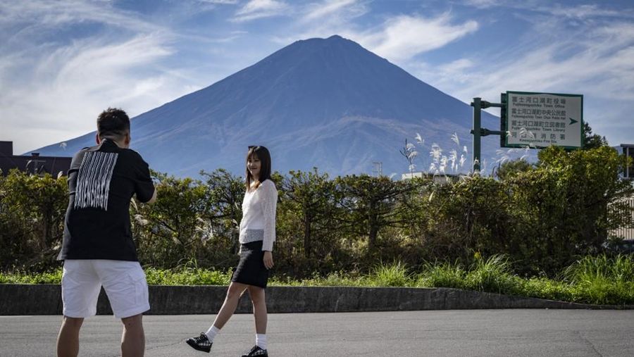 Warga beraktivitas dengan latar belakang Gunung Fuji, gunung tertinggi di Jepang dengan ketinggian 3.776 meter (12.460 kaki), di Fujikawaguchiko, prefektur Yamanashi pada tanggal 31 Oktober 2024. (AFP/YUICHI YAMAZAKI)