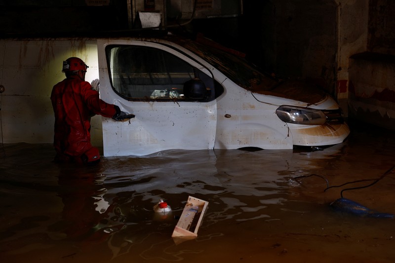 EUROPE-WEATHER/SPAIN-STORM A firefighter searches for possible victims inside cars damaged following heavy rains that caused floods, in Alfafar, Valencia, Spain, November 1, 2024. REUTERS/Susana Vera