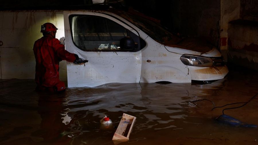 A firefighter searches for possible victims inside cars damaged following heavy rains that caused floods, in Alfafar, Valencia, Spain, November 1, 2024. REUTERS/Susana Vera