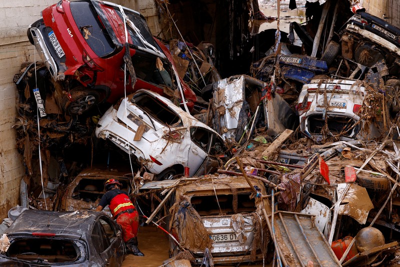 A firefighter searches for possible victims inside cars damaged following heavy rains that caused floods, in Alfafar, Valencia, Spain, November 1, 2024. REUTERS/Susana Vera