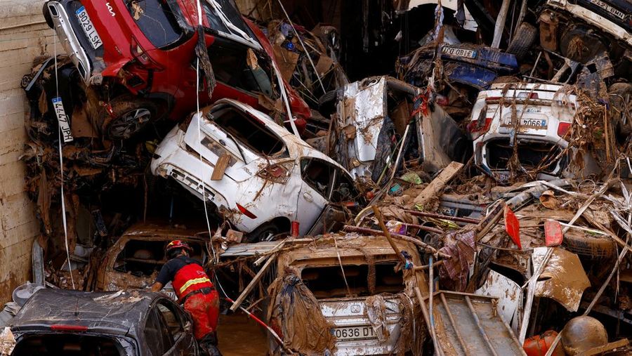 A firefighter searches for possible victims inside cars damaged following heavy rains that caused floods, in Alfafar, Valencia, Spain, November 1, 2024. REUTERS/Susana Vera