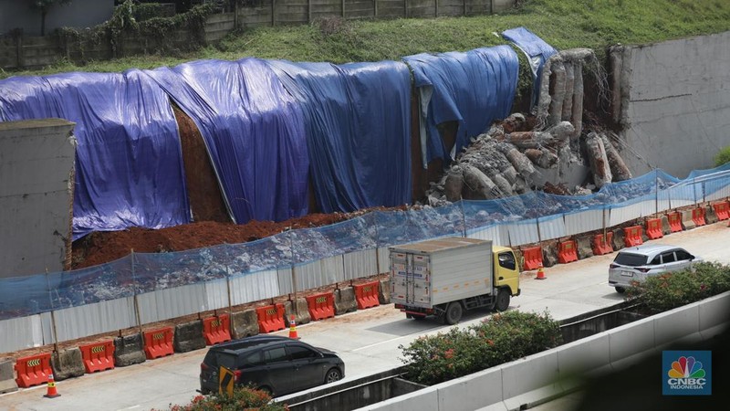 Sejumlah pekerja membersihkan sisa-sisa tanah yang memasuki ruas jalan Tol Serpong - Cinere, Senin (4/11/2024). (CNBC Indonesia/Tri Susilo)